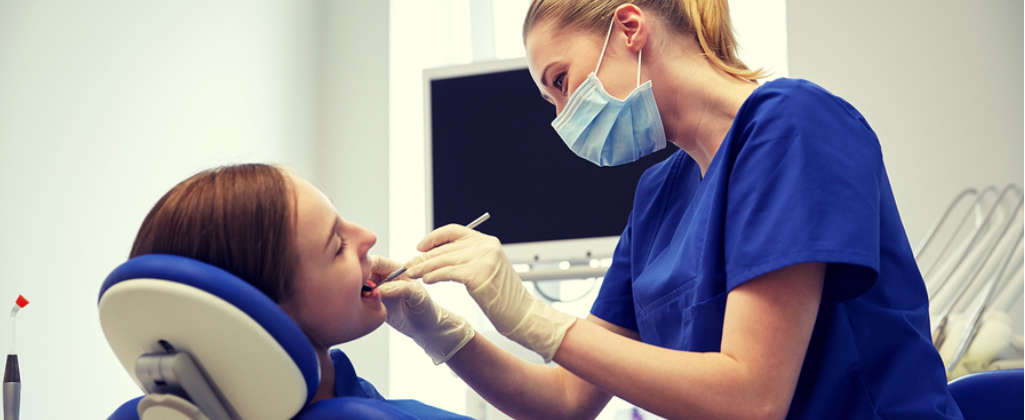 The dentist performs the procedure on a young woman.