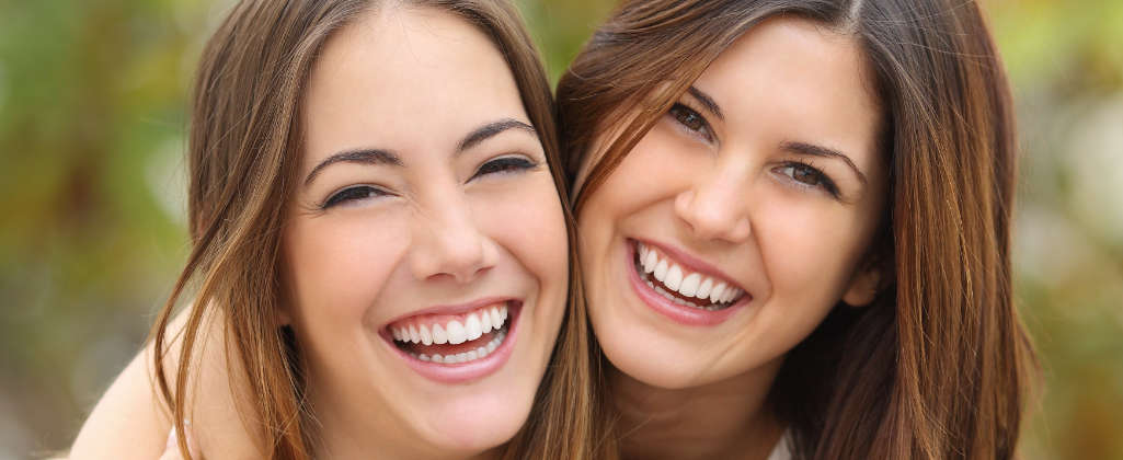 Two young women laugh while presenting beautiful smiles.