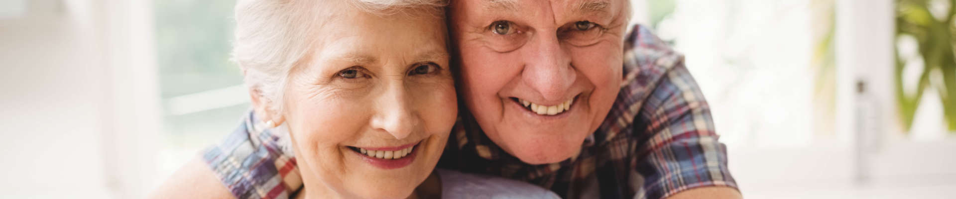 A hugging senior couple smiling.