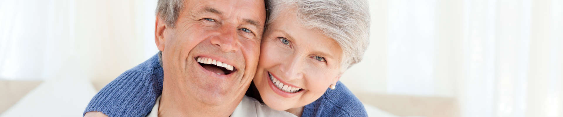 A pair of laughing, older people. They embrace.