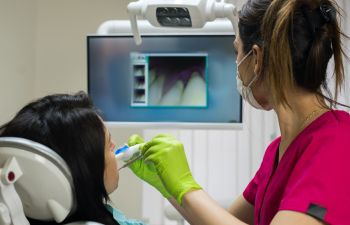 Dentist examining woman's gums and teeth using an intraoral camera.